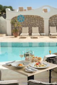 a table with food and wine glasses next to a swimming pool at La Residenza Capri in Capri