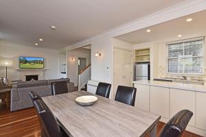 a kitchen and living room with a wooden table and chairs at Villa 2br Grange Villa located within Cypress Lakes Resort in Pokolbin