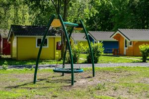 un parque infantil con columpio en un patio en EuroParcs Het Amsterdamse Bos en Amstelveen