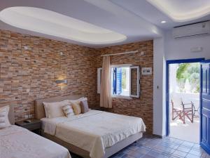 a bedroom with two beds and a brick wall at Arapiou Apartments in Perivolos