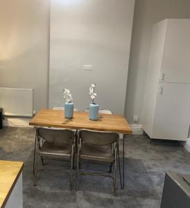 a wooden table with two chairs and two vases on it at 1 bedroom spacious apartment in Lytham St Annes +7 photos