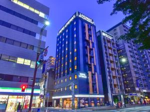 HOTEL LiVEMAX Hakata Nakasu في فوكوكا: مبنى أزرق طويل على شارع المدينة في الليل