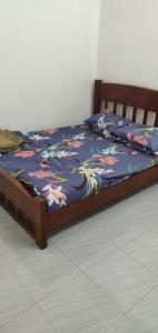 Raudah Homestay Kuala Nerang في Kuala Nerang: سرير مع لحاف أزرق عليه زهور