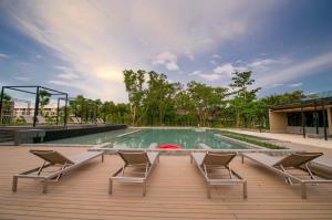 a swimming pool with four chairs and a deck at The Gallery Hotel Nai Harn - SHA Plus in Nai Harn Beach