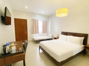 a bedroom with a bed and a desk and a chair at HARMAN SUITES Moalboal in Moalboal +28 photos