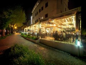 a group of people standing outside of a store at night at Postumia Hotel Design in Oderzo