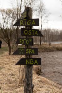 a wooden sign with signs on a pole at Piešupīte in Staburags