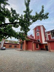 un edificio rojo con un árbol delante de él en T&S Apart-Hotel en Chernivtsi