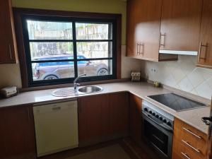 eine Küche mit einem Waschbecken und einem Fenster in der Unterkunft Casa 2 habitaciones con piscina y cenador al aire libre in Pontevedra