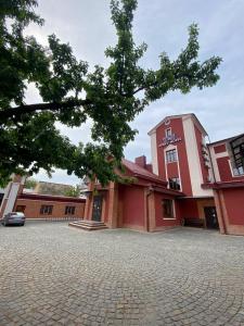 ein rotes Gebäude mit einem Baum davor in der Unterkunft T&S Apart-Hotel in Czernowitz