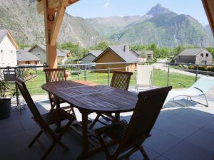 - une table et des chaises en bois sur une terrasse couverte avec des montagnes dans l'établissement Lodge Fabisa, à Le Vert
