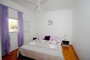 a white bedroom with a bed and a ceiling fan at Holiday House Roza in Vela Luka +22 photos