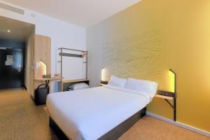 een slaapkamer met een groot wit bed en een gele muur bij B&B HOTEL Le Touquet in Cucq