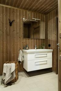 ein Badezimmer mit weißem Waschbecken und Holzwänden in der Unterkunft Cozy modern holiday villa with electric car charging, sauna and fireplace in Øyer