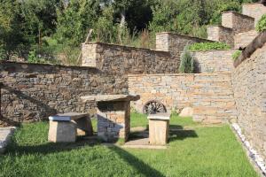 a stone wall with a wheel in a yard at Дренковите Къщи Drenkovi Houses in Kovačevica +79 photos