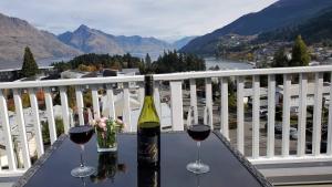 two glasses of wine sitting on a table on a balcony at Lakeview with amazing Rooftop with 10mins walk to town镇上湖景三室套房 in Queenstown