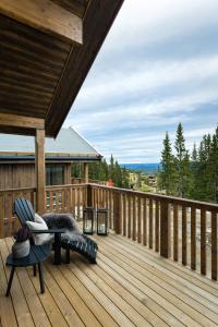 una terraza de madera con un banco y una silla. en Cozy modern holiday villa with electric car charging, sauna and fireplace, en Øyer