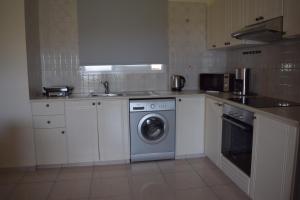 a kitchen with white cabinets and a washing machine at Eden Heights Sea View Apartment 203 - By IMH Travel & Tours in Paphos City