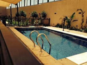 a large swimming pool with a metal rail in a building at Lijam Apartments in Amman