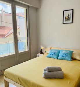 sypialnia z łóżkiem z niebieskimi poduszkami i oknem w obiekcie KASA VOYTIER Parking privé & Wifi - Balcon & Ascenseur w mieście Saint Etienne