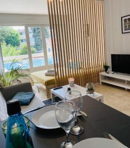 sala de estar con mesa y 2 copas de vino en KASA VOYTIER Parking privé & Wifi - Balcon & Ascenseur en Saint Etienne