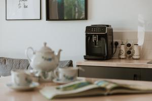 a table with a tea pot and a toaster and cups at Leśny Apartament - Shuuumi Las in Chmielno
