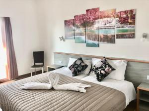 ロカルノにあるHotel Garni Montaldiのベッドルーム1室(壁に4つの絵画が飾られたベッド1台付)
