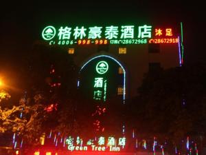 un panneau éclairé devant une auberge arborée verdoyante dans l'établissement GreenTree Inn Guangzhou Panyu Chimelong Paradise Business Hotel, à Canton
