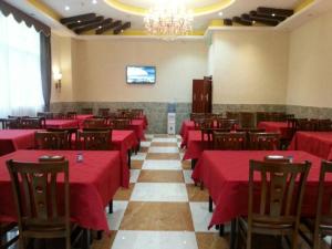 une salle à manger avec des tables et des chaises rouges et un écran dans l'établissement GreenTree Inn Guangzhou Panyu Chimelong Paradise Business Hotel, à Canton