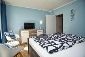 um quarto com uma cama, uma televisão e uma cadeira em F-1010 Strandhaus Mönchgut Bed&Breakfast DZ 25 Garten, strandnah, inkl Frühstück em Lobbe