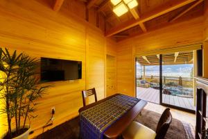 a wooden room with a bed and a tv and a balcony at Yufuin-Sanso Waremokou in Yufuin