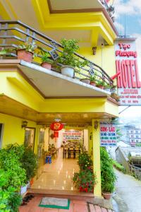 een geel gebouw met tafels en potplanten bij Tạo Phượng Sa Pa Hotel in Sa Pa