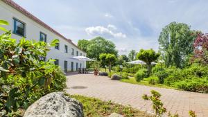 einen Backsteinsteg neben einem Gebäude mit Sonnenschirmen in der Unterkunft Seepark Hotel am Wandlitzsee in Wandlitz