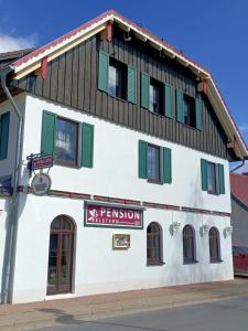 ein Gebäude mit grünen Rollläden und einem Schild darauf in der Unterkunft Pension Drei Elstern in Schierke