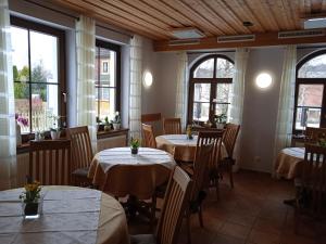 a dining room with tables and chairs and windows at Pension Drei Elstern in Schierke