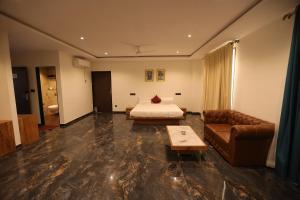 ein Hotelzimmer mit einem Bett und einem Sofa in der Unterkunft The Heritage Conventions in Sāgar
