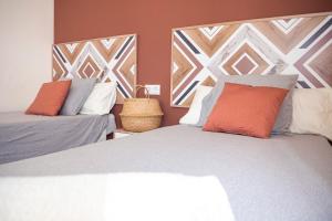 een slaapkamer met 2 bedden met oranje en grijze kussens bij Apartamento AGUADULCE in Sanlúcar de Barrameda