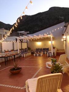 d'une terrasse avec des chaises blanches, des tables et des lumières. dans l'établissement NA' SCICCHERIA HOME, à Castellammare del Golfo