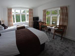 法爾茅斯的住宿－The Grove Falmouth，酒店客房带两张床和一张桌子以及椅子。