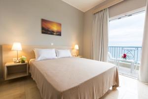 a bedroom with a large bed and a large window at Corfu Aquamarine in Nótos