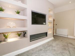 uma sala de estar com lareira e uma televisão de ecrã plano em Carriage House em Macclesfield