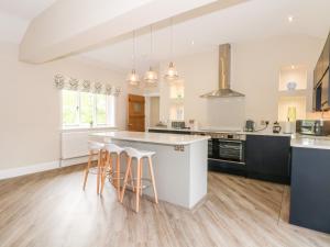 una cucina con banconi bianchi e un'isola con sgabelli da bar di Carriage House a Macclesfield