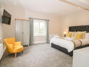 ein Schlafzimmer mit einem großen Bett und einem Stuhl in der Unterkunft Carriage House in Macclesfield