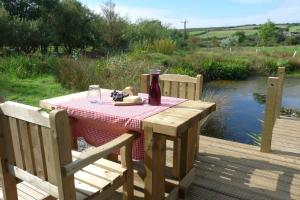 a picnic table with a bottle of wine on a deck at Shepherds Hut on Cornish Smallholding in Penzance