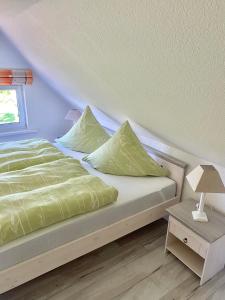 a bed with green sheets and pillows in a room at ''Zur alten Boddenfischerei'' Ferienwohnung Weitblick in Saal