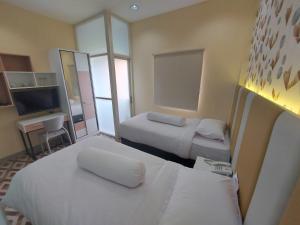 pokój hotelowy z 2 łóżkami i telewizorem w obiekcie Rumah Familiku 1 Syariah w mieście Wonocolo