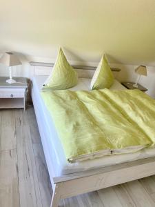 a large bed with yellow sheets and pillows on it at ''Zur alten Boddenfischerei'' Ferienwohnung Weitblick in Saal