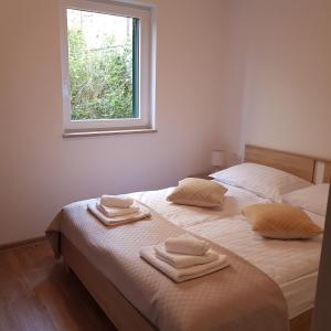 a white bedroom with two beds with towels on them at Apartment Katerina in Supetar