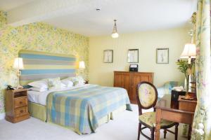 a bedroom with a bed and a desk and a chair at Holbeck Ghyll Country House Hotel with Stunning Lake Views in Windermere