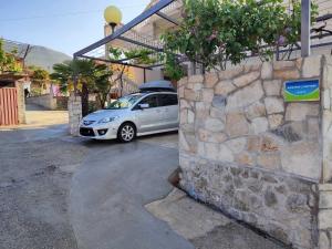 een auto geparkeerd op een parkeerplaats naast een stenen muur bij Nemanja in Trebinje